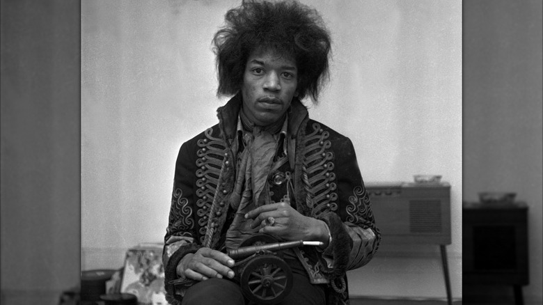 Jimi Hendrix in a martial-style coat holding a toy cannon
