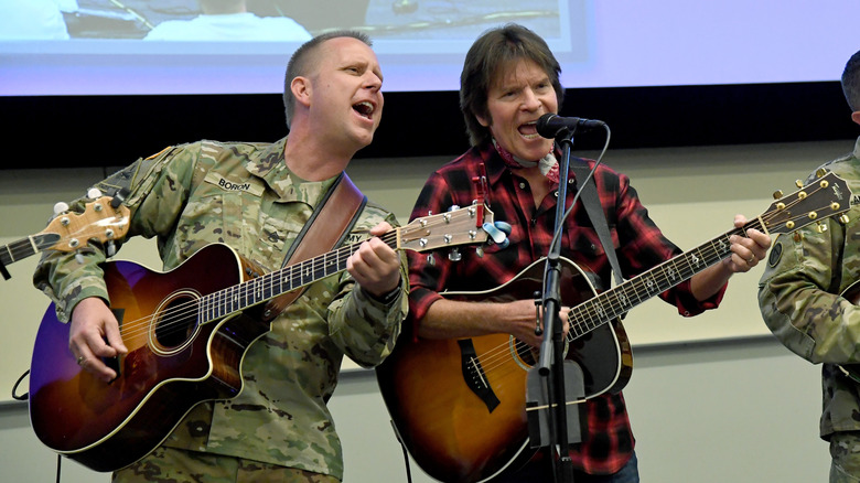 John Fogerty performing with several members of the military wearing camo
