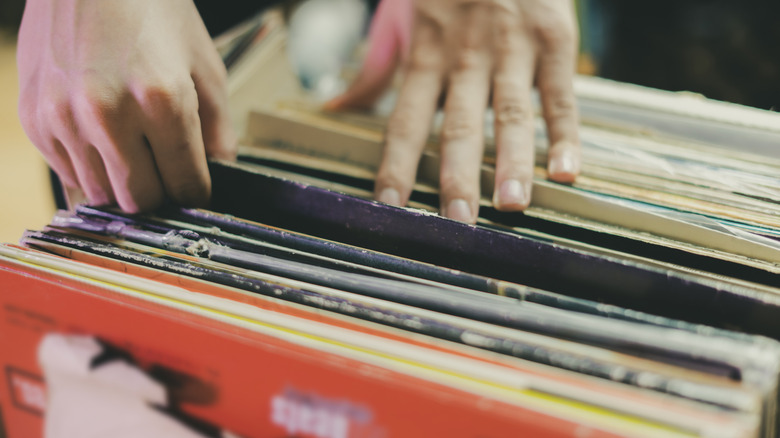 Closeup hands going through collection of vinyl albums in covers