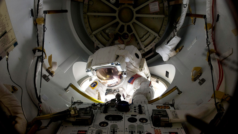 Astronaut in suit entering airlock inside International Space Station, 2011