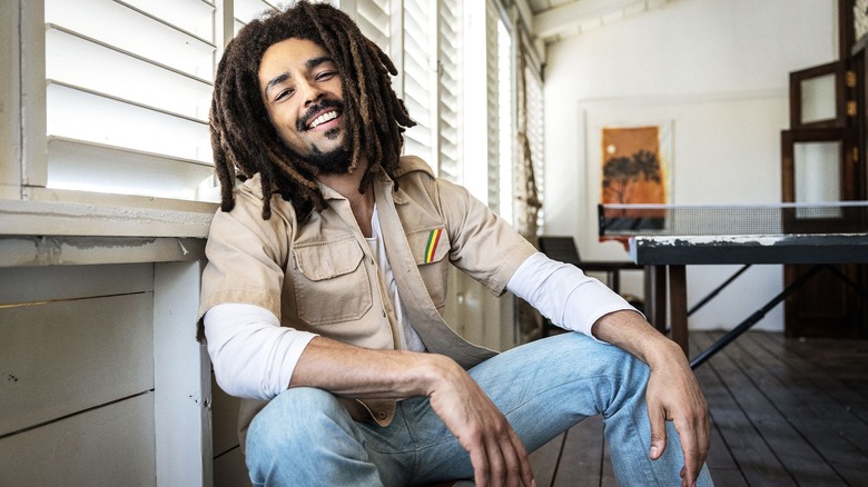 Kingsley Ben-Adir as Bob Marley sitting indoors smiling