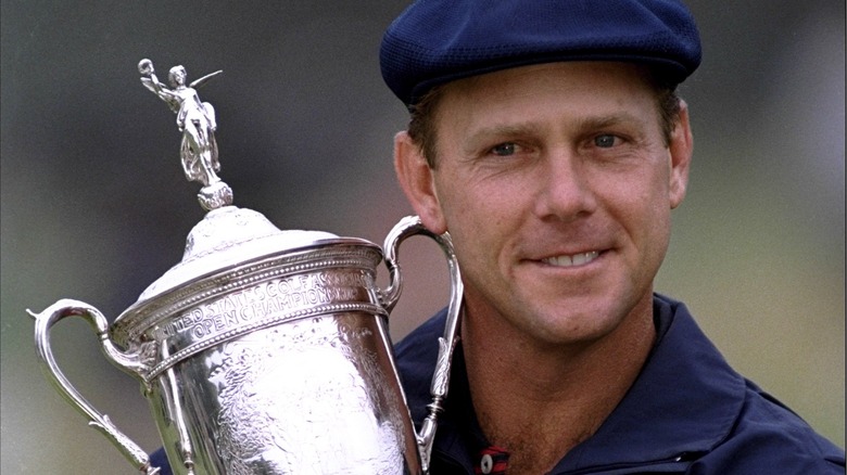 Payne Stewart holding trophy smiling blue hat