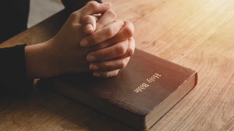 hands praying on Bible