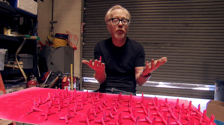 Adam Savage standing in front of pink painted road spikes