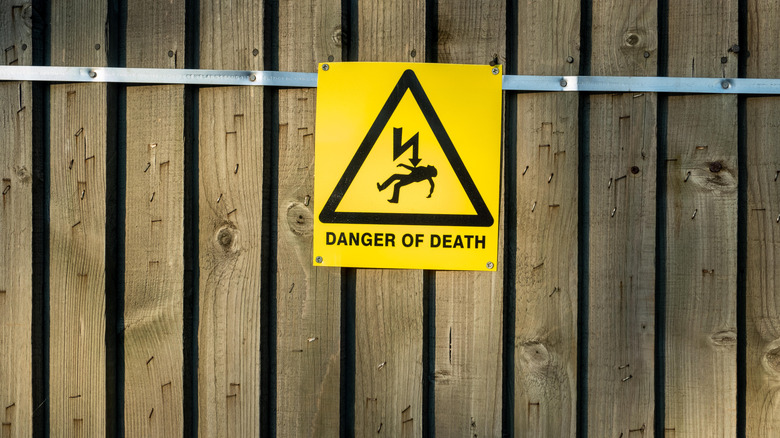 Danger electricity sign closeup on fence