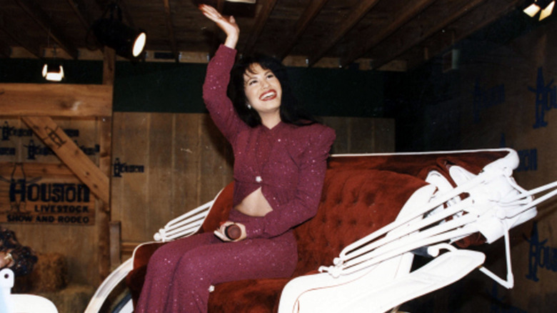 selena smiling and waving on stage in a chariot