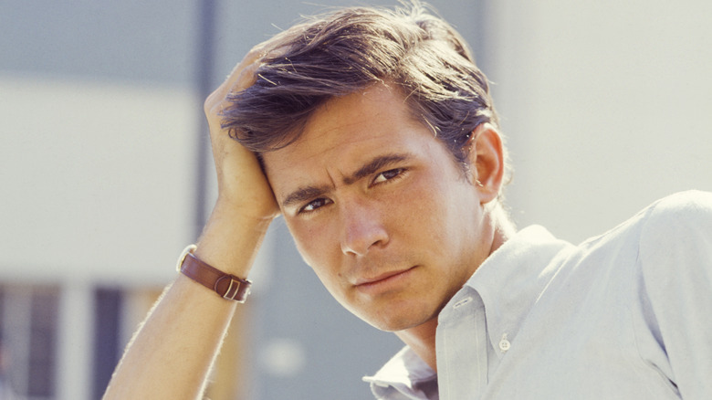 Anthony Perkins leans on a car