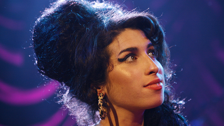 Amy Winehouse grinning and looking up and off