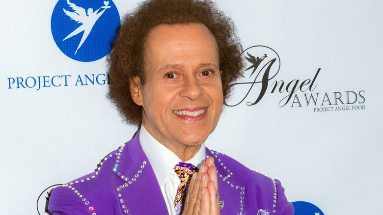 Richard Simmons grinning in purple jacket