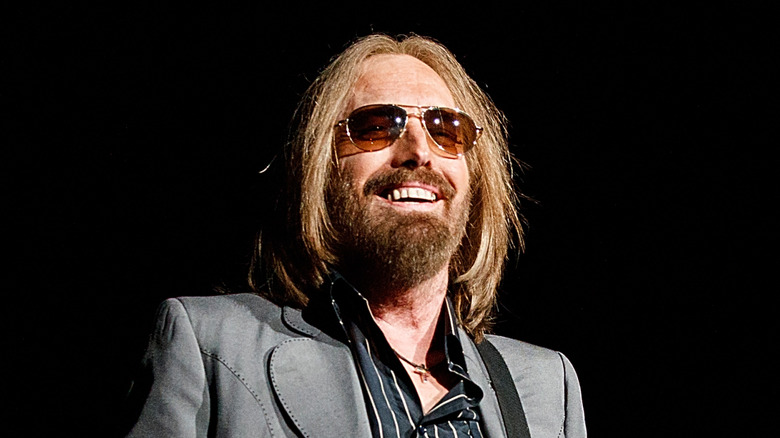 Tom Petty smiles on stage in gray suit