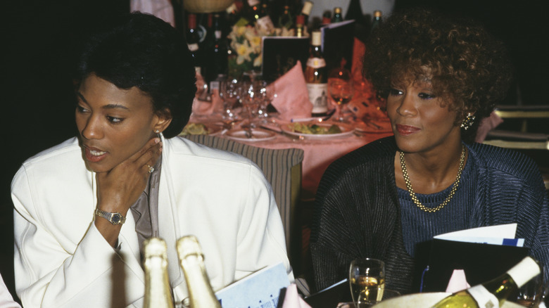 Robyn Crawford and Whitney Houston sitting at table