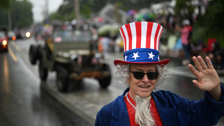 Person dressed in patriotic gear in front of a blurred parade background