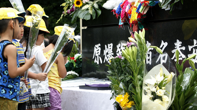 children leaving flowers at nagasaki memorial