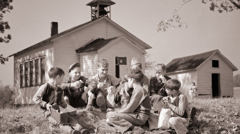 CHildren take a lunch break outside one-room school, 1950