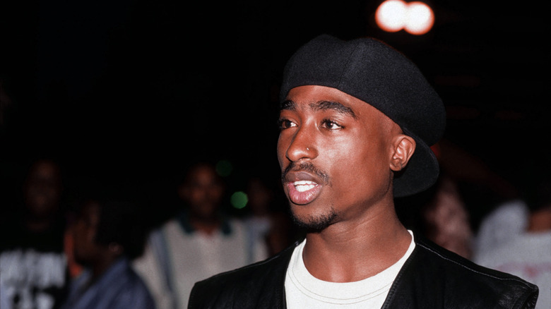 Tupac Shakur wearing a black cap