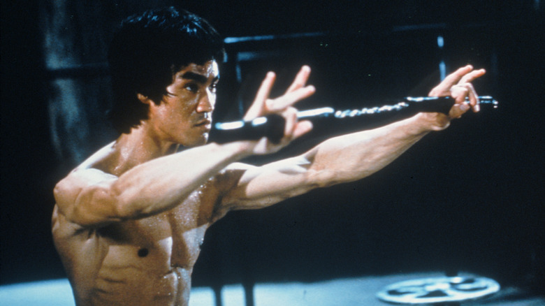 Bruce Lee's Lee holding a weapon in front of him in Enter the Dragon