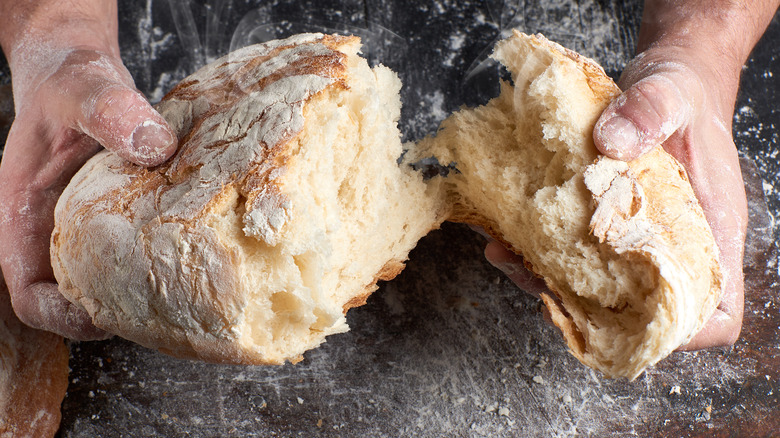 hands breaking a loaf of bread