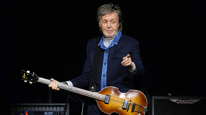 Paul McCartney holding a guitar and pointing