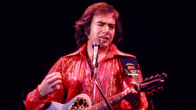 Neil Diamond performing with guitar in red shirt on stage