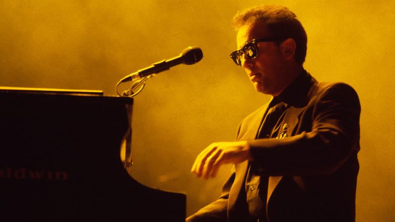 Billy Joel sat playing piano on stage wearing sunglasses