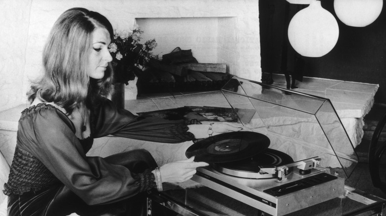 woman listening to an lp on a record player 1970s