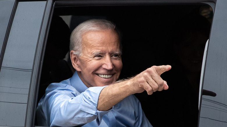 Joe Biden pointing out of a car