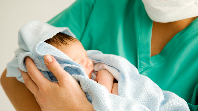 newborn held by nurse