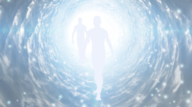 figures walking into tunnel bright light
