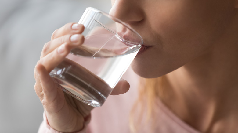 person drinking water from glass