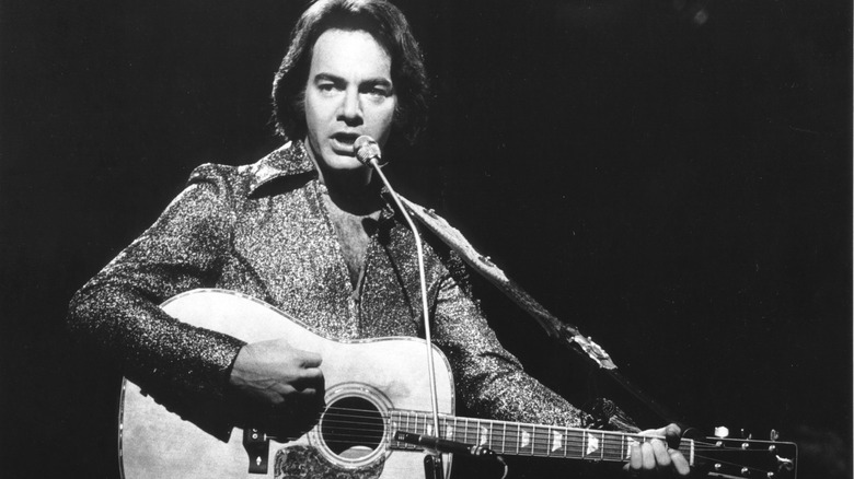 Neil Diamond plays a guitar on stage