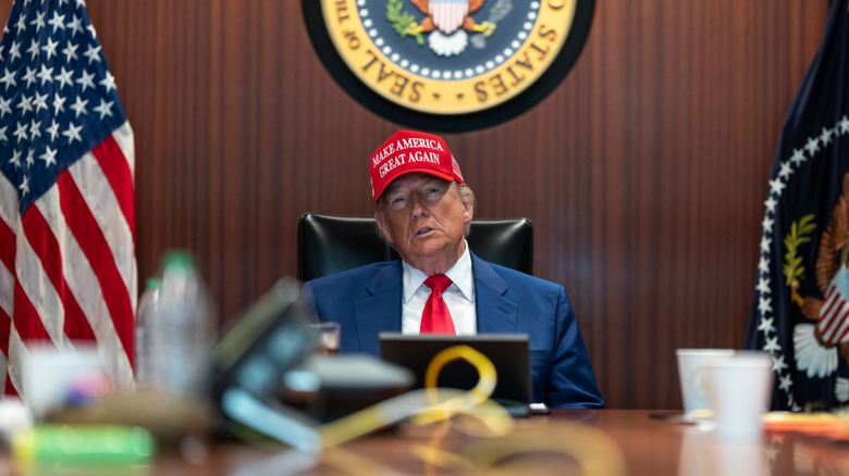 Donald Trump in his office wearing a MAGA hat
