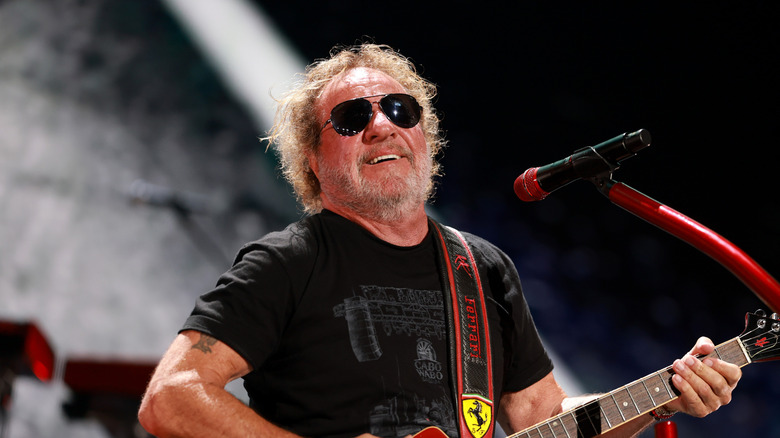 Sammy Hagar wearing sunglasses and playing guitar on stage