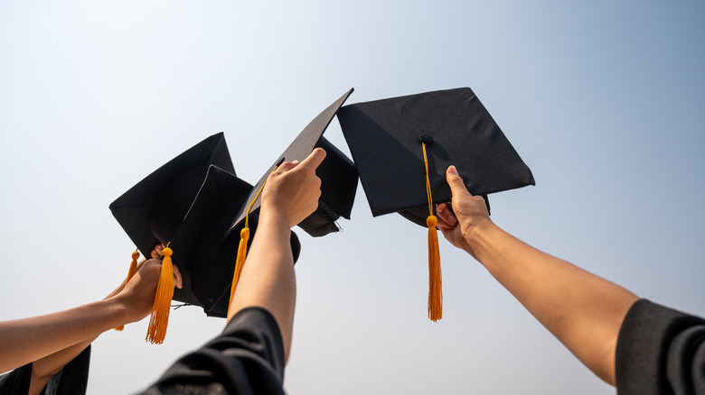 college graduates hold mortarboards