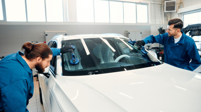 Mechanics replacing a windshield on a modern car