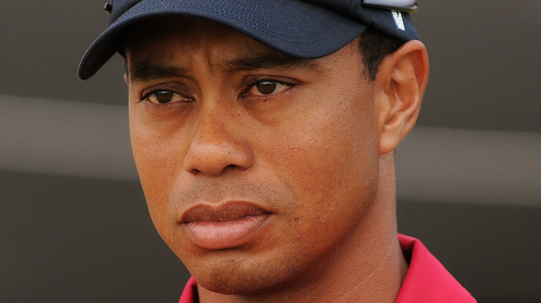 Tiger Woods in red shirt and black cap not smiling