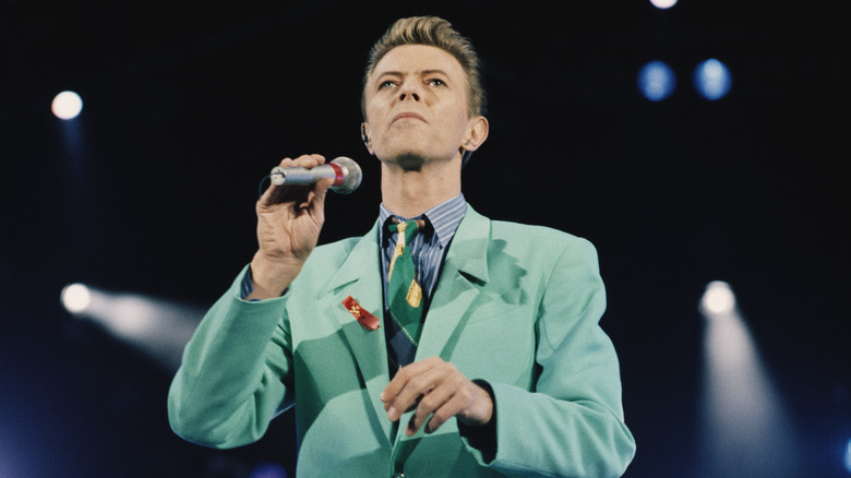 David Bowie onstage in a suit holding microphone