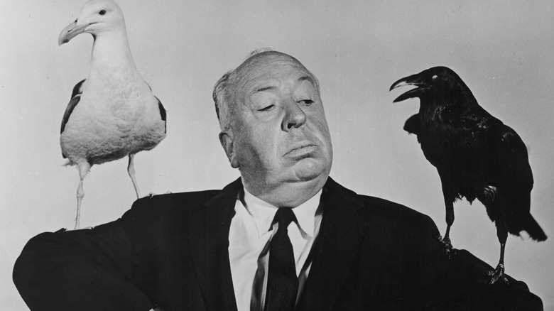 Alfred Hitchcock posing with birds on his shoulders