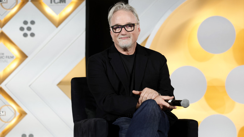 David Fincher sitting on a chair with a microphone in his hand