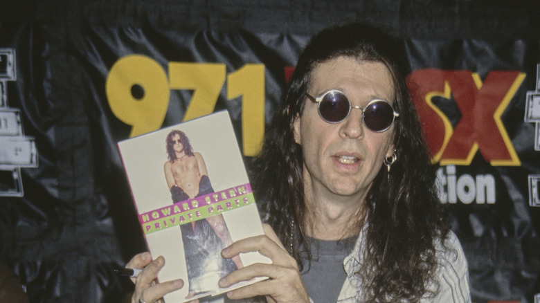 Howard Stern holding a copy of his book Private Parts wearing sunglasses