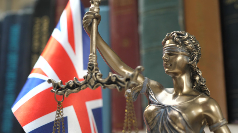 Lady Justice statue stands before British flag