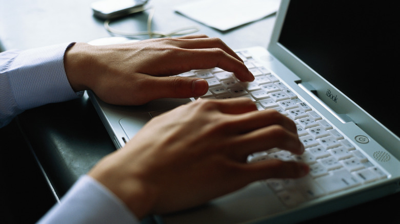 hands typing on laptop keyboard