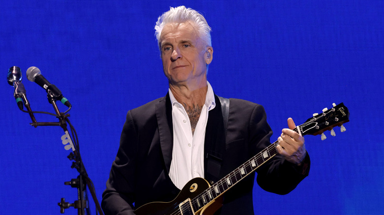 Neil Giraldo playing guitar in a suit on stage