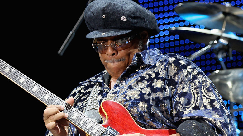Al McKay plays red guitar onstage drums background