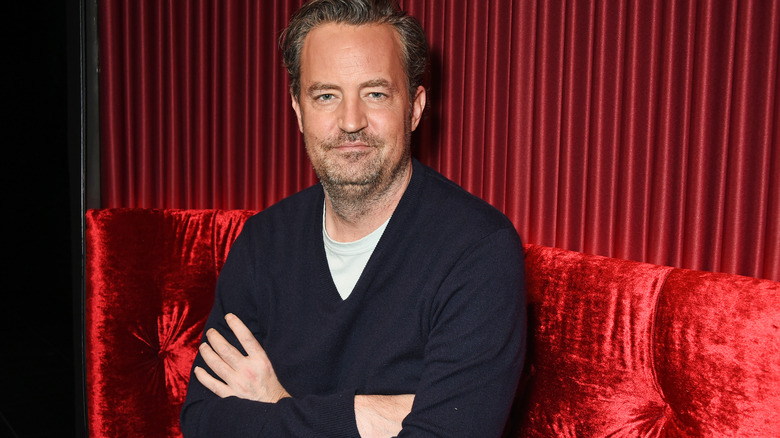 Matthew Perry on a red sofa