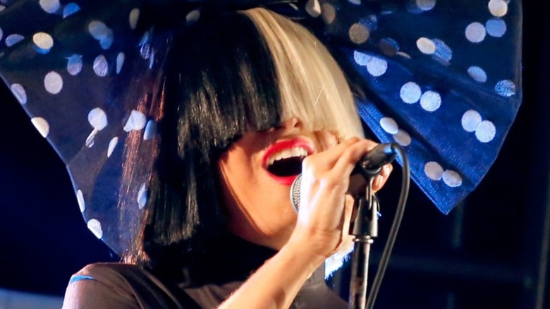 Sia performing with a wig and bow