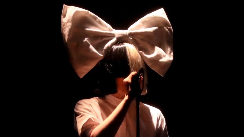 Sia performing wearing a wig and bow
