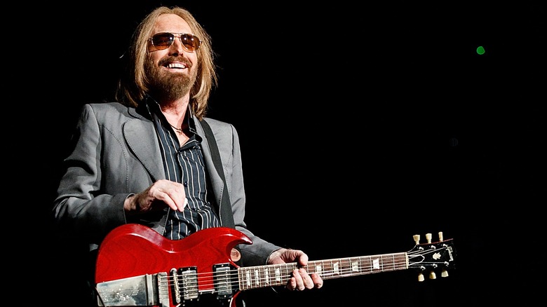 Tom Petty smiling and holding red guitar