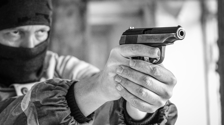 Man black balaclava holding up pistol