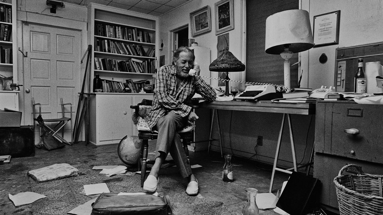 Tennessee Williams seated in messy room on the phone