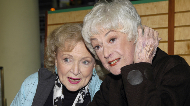 Betty White leaning into Bea Arthur at table panel talk